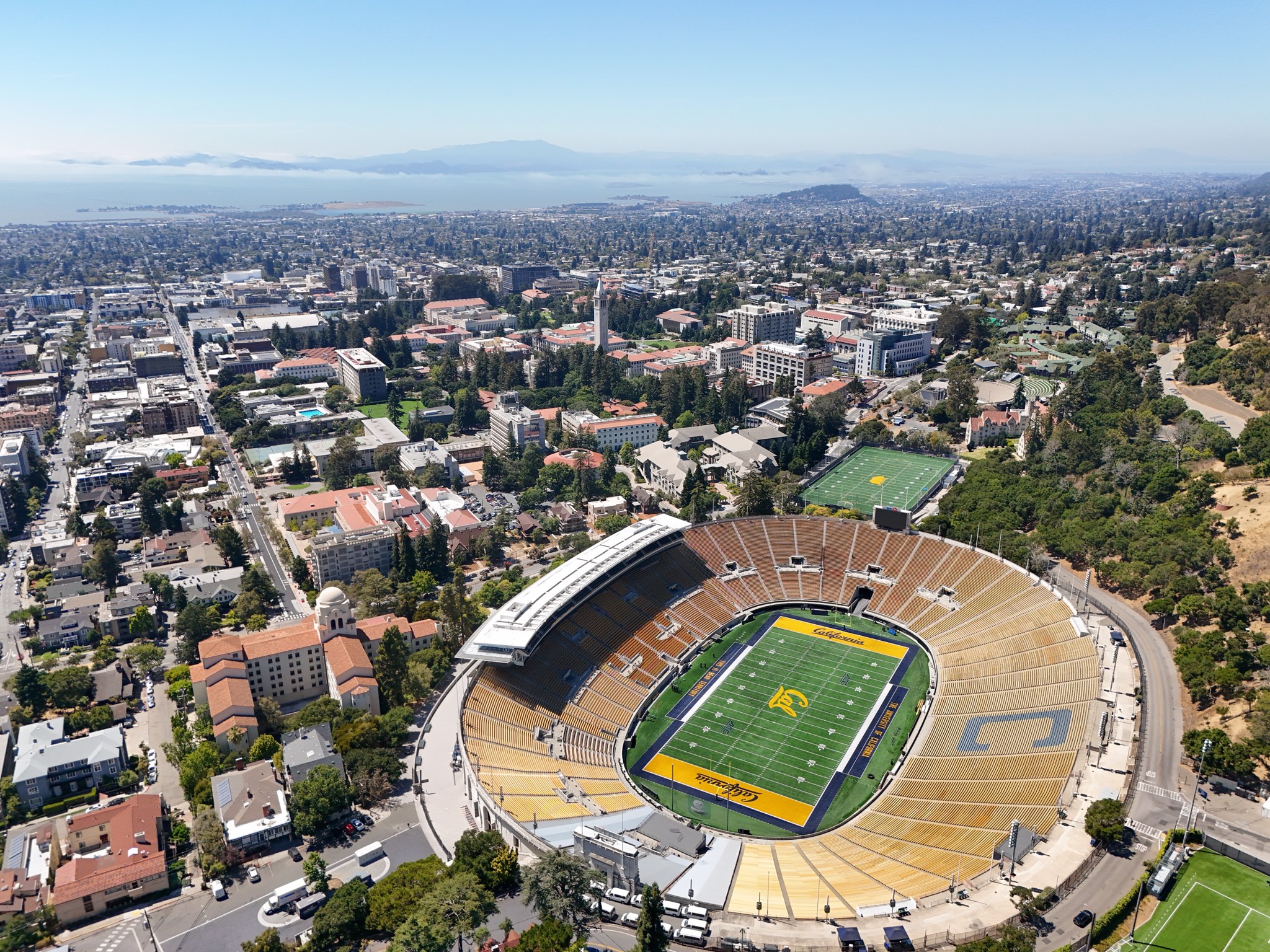 Aerial view over Berkeley with the UC Berkeley campus, the Campanile, and San Francisco Bay beyond.