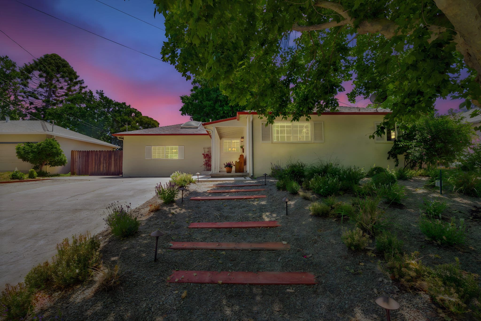 A Bay Vista–managed Bay Area home at twilight, lit warmly under a pink-and-purple evening sky.